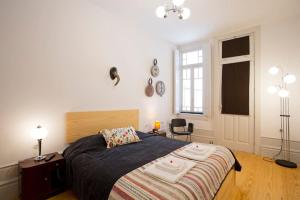 Un dormitorio con una cama y una silla y una ventana. en 14º Esquadra — Cais das Pedras Guest House, en Oporto