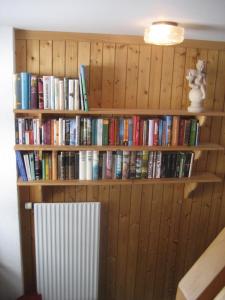 a book shelf filled with books next to a radiator at B&B Pension Lärch in Obergesteln