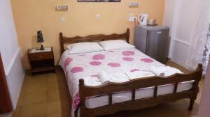 a bedroom with a bed with a pink and white comforter at Christina Pension in Karterados