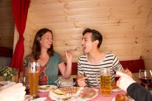 Ein Mann und eine Frau sitzen am Tisch und essen Essen. in der Unterkunft Campingplatz am Hünstein in Nohra