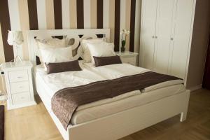 a bedroom with a large white bed with striped walls at Lux new white apartment in Novi Sad