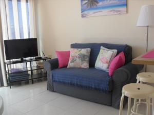salon z niebieską kanapą i różowymi poduszkami w obiekcie Irene Apartment w Puerto del Carmen