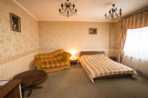 um quarto com uma cama, um sofá e uma cadeira em Magnat Lux Hotel em Chernivtsi