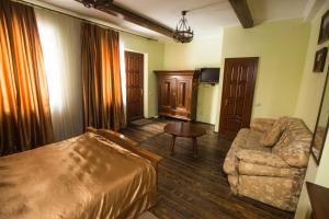 a bedroom with a bed and a couch and a chair at Magnat Lux Hotel in Chernivtsi