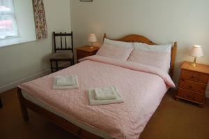 スライゴにあるArdtarmon Barn Cottageのピンクベッド1台(枕2つ付)が備わるベッドルーム1室が備わります。