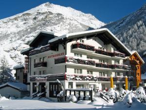 a building in the snow with a mountain in the background at Hotel Restaurant Mattmarkblick in Saas-Almagell +31 photos