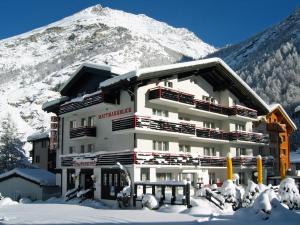 a building in the snow with a mountain in the background at Hotel Restaurant Mattmarkblick in Saas-Almagell