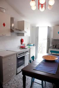 a kitchen with a table and a kitchen with a stove and a sink at Casa Allegra e Colorata in Badolato