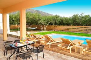 a patio with a table and chairs next to a swimming pool at White Lake Holiday House in Elafonisi