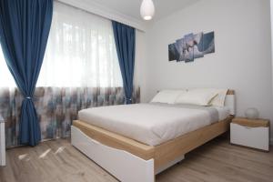 a bedroom with a large bed with blue curtains at M&N Central Apartment in Plovdiv
