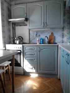 a kitchen with blue cabinets and a table and a stove at Comfortable flat near the Dnieper river in Kyiv in Kyiv