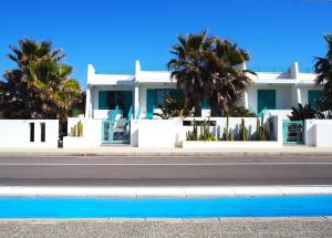 a white house with palm trees in front of a street at Terrazze Del Mare in Torre Suda