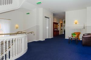um corredor com uma escada e um sofá e uma cadeira em Kurhaus Hotel em Wyk auf Föhr
