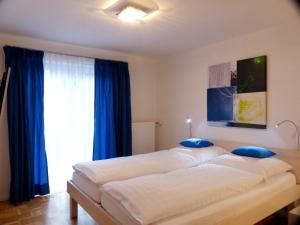 ガルミッシュ・パルテンキルヒェンにあるWolke7の青いカーテンが備わる客室のベッド2台