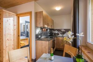 a kitchen with wooden cabinets and a table and chairs at Refugium Dolomiten & Chalet in Sillian