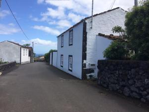 an empty street with a white house and a stone wall at Casa do Ginjal in Santo Antonio