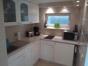 a kitchen with white cabinets and a sink and a window at Teltow Ferienwohnung in Teltow