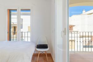 a bedroom with a bed and a chair next to a window at Rooms Cozy House in Ses Salines
