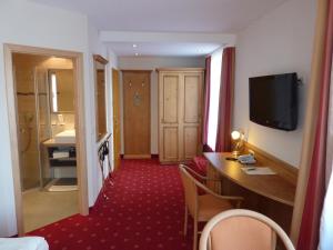 a hotel room with a desk and a television and a bathroom at Hotel Holl in Schongau