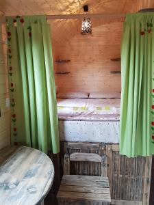 Cabaña pequeña con mesa y cortinas verdes en La roulotte de Chiroubles en Chiroubles