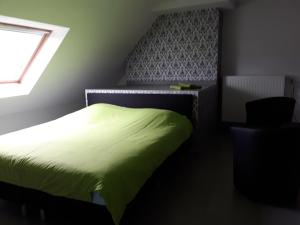 a bedroom with a green bed and a window at Discover in Ieper