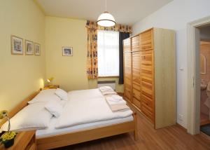 カルロヴィ・ヴァリにあるApartmán Ondřejskáのベッドルーム1室(白いシーツと木製キャビネット付)