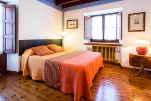 a bedroom with a bed with an orange blanket at Apartamentos La Casona De Vidiago in Vidiago