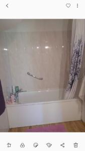 uma banheira branca com uma cortina de chuveiro na casa de banho em Le Hameau des Ecrins Station 1800 em Puy-Saint-Vincent
