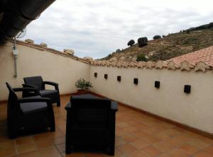 a patio with two chairs and a wall at El Rincón del Gallo in Tronchón