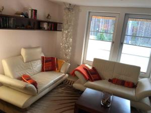 a living room with two white leather chairs and windows at Ferienhaus Duenenwald 1 _LANG in Ostseebad Karlshagen