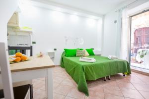 Cama verde en habitación blanca con mesa en Casa Smeraldo, en Cefalú