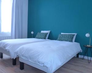 a bedroom with two beds with blue walls at Maison En Ville in Niort