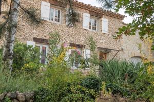 una antigua casa de ladrillo con ventanas y plantas blancas en Mas des Coccinelles, en Mollans-sur-Ouvèze