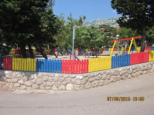 a colorful fence in a park with a playground at Danica Karlobag in Karlobag
