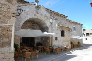 an outdoor restaurant with tables and chairs and an umbrella at Hotel Rural La Enhorcadora in Portillo