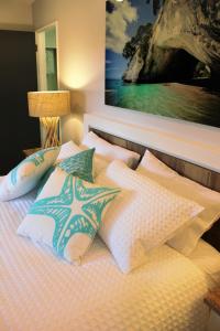 ein Bett mit Kissen und ein Gemälde an der Wand in der Unterkunft Close to beach in Auckland