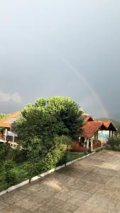 a tree in front of a house with a building at Pousada Lambari Montanha Hotel in Lambari