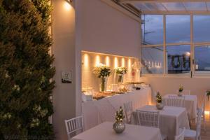 restauracja z białymi stołami, białymi krzesłami i światłami w obiekcie Hotel Donatello Imola w mieście Imola +37 zdjęć
