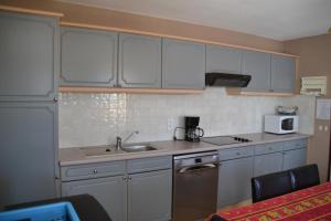 a kitchen with white cabinets and a sink at Résidence Niccola in Vidauban