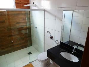 a bathroom with a toilet and a glass shower at Hotel Monte Carlo Uberlândia in Uberlândia
