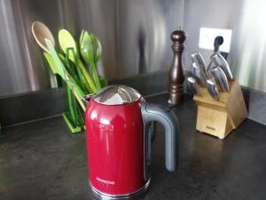 a red jug on a counter with a bunch of utensils at Penthouse bij Leopoldpark in Ostend