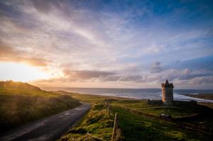 a building on the side of a road next to the ocean at Fairwinds Guest Accommodation in Doolin +30 photos