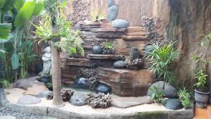 una cascada de piedra en un jardín con plantas en The Arya guest house, en Gilimanuk
