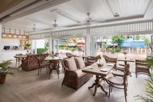 um restaurante com cadeiras de vime, mesas e janelas em Casa Vimaya Riverside em Bangkok