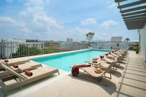 a pool on the roof of a building with lounge chairs at Casa Vimaya Riverside in Bangkok