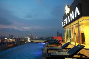 a swimming pool on the roof of a building with chairs at Levana Pattaya Hotel - SHA Extra Plus in Pattaya