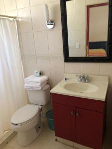 a bathroom with a toilet and a sink and a mirror at Hotel Calafia in La Paz