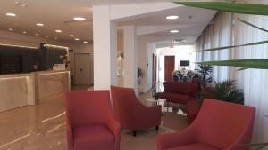 una sala d'attesa con sedie rosse e un tavolo di Hotel Grifone a Rimini