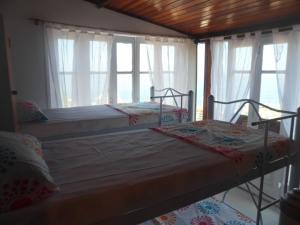 two beds sitting in a room with windows at Mar da Babilônia Hostel in Rio de Janeiro