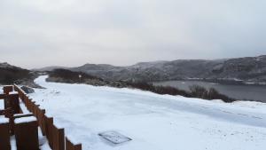 a road covered in snow next to a body of water at Achmelvich View self catering in Lochinver